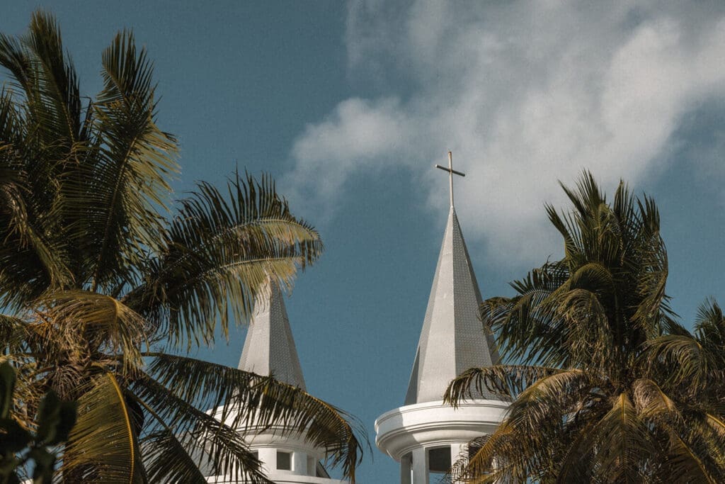 Two Church spires adorned with crosses between palm trees on Rote Island